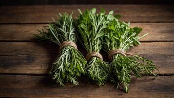 Three bundles of fresh herbs tied with twine on a wooden surface. photo
