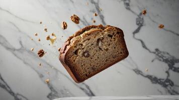 A slice of banana bread floating above a marble surface, surrounded by walnut pieces. photo