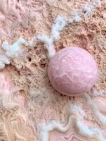 Closeup of a pink marble sphere on a textured background photo