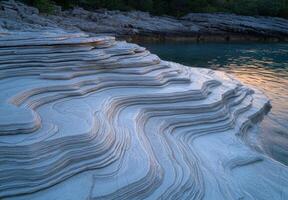 Stunning layered rock formations by the water photo