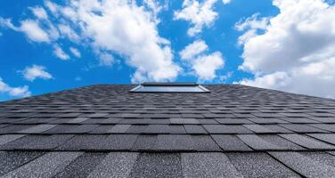 Asphalt shingle roof against blue sky with clouds photo