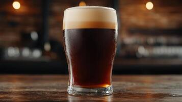 Frothy dark beer in a glass on a wooden table photo