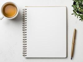 blank notebook with pen and cup of tea on white table photo