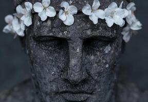 close up of stone buddha statue with white flowers photo