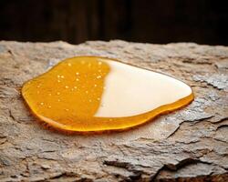 Honey dripping from a honeycomb on a rustic wooden surface photo