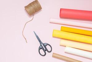 Crafting tools on pastel background with colorful rolls of paper. photo