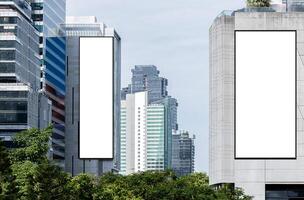 Two white mock up vertical large LED display billboard on tower building with blue sky background .clipping path for mockup photo
