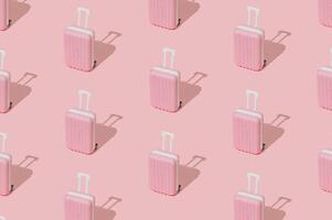 Trendy pattern made of pink suitcase on pastel pink background. Minimal travel concept. Trendy vacation idea. photo