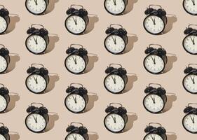 Trendy sunlight pattern made with retro alarm clock on pastel cream background. Minimal time concept. photo