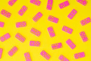 Trendy pattern made of pink dominoes on yellow background. Minimal board game concept. Creative tile based game pattern backdrop. Colorful domino flat lay idea. photo
