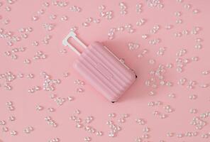 Trendy pattern composition made of diamonds with pink suitcase on pastel pink background. Minimal creative travel concept. Fancy vacation idea. Flat lay. photo