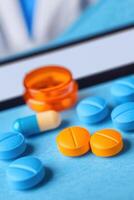 Colorful pills and capsule on a blue background, with a bottle in the background. photo