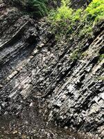 Steep rock formation with lush greenery in a natural setting photo