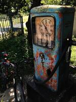 Aged vintage gas pump beside a bicycle in outdoor setting photo