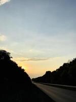Serene sunset over an empty road lined with trees photo