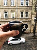 Hand holding a ceramic coffee cup with urban background photo