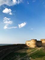 Ancient stone fortress under a bright blue sky with scattered clouds. Bilhorod-Dnistrovskyi fortress, or Akkerman Kokot, Ukraine. photo