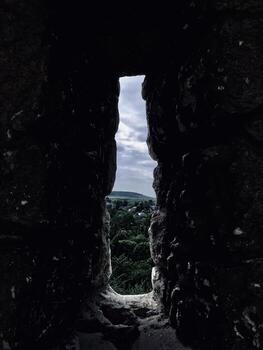 View of a distant village through an ancient stone window photo