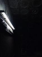Dimly lit industrial corridor with a glowing fluorescent light photo