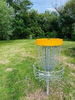 Disc golf basket in a scenic park setting with trees and grass photo