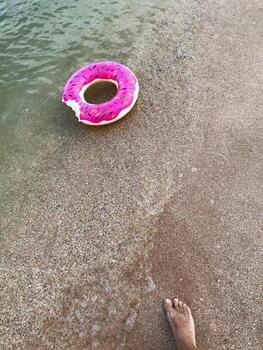 Inflatable donut float on sandy beach with gentle waves photo