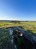 Solitary figure on natural rock bridge in a green landscape photo