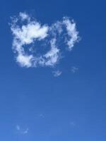 Fluffy white cloud shaped like a heart in blue sky photo