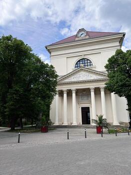 Historic building with columns and clock against a lush green backdrop in Slavkov u Brna, Czech Republic. photo