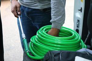 A man holding a green hose in the back of a van photo