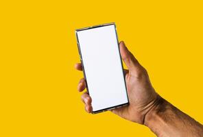 Male hands holding a mobile isolated in yellow background. Space for text or logo. photo