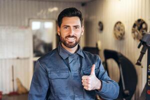 Portrait of smiling, professional repairman wearing uniform, looking at camera, showing thumb up photo