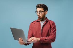 Excited, shocked Latin man, professional programmer using laptop, copywriter typing on keyboard photo