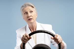 Senior woman, driver businesswoman holding steering wheel looking away with open mouth photo