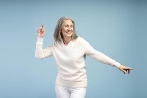Portrait of happy, smiling mature woman with closed eyes, dancing, having fun photo