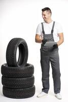 Mechanic using digital tablet next to stack of tires in auto shop photo