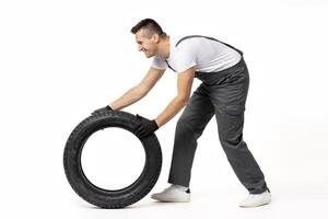 Mechanic pushing tire in studio on white background photo