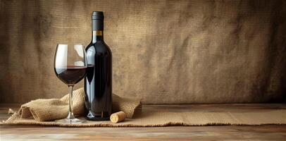 One glass with red wine and a bottle of wine on a background of undyed fabric, burlap, copy space. photo