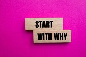 Start with why message written on wooden blocks with pink background. Conceptual start with why symbol. Copy space. photo