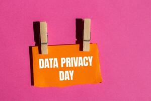 Data privacy day message written on ripped torn orange paper piece with pink background. Conceptual data privacy day symbol. Copy space. photo