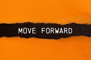 Move forward message written on ripped torn orange paper with black background. Conceptual move forward symbol. Copy space. photo
