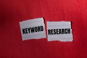 Keyword research message written on ripped torn paper piece with red background. Conceptual keyword researchs symbol. Copy space. photo