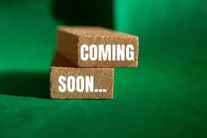 Coming soon message written on wooden blocks with green background. Conceptual coming soon symbol. Copy space. photo
