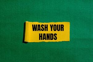 Wash your hands message written on ripped torn yellow paper piece with green background. Conceptual wash your hands symbol. Copy space. photo