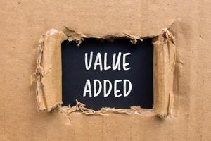 Value added message written on ripped torn cardboard paper with black background. Conceptual value added symbol. Copy space. photo