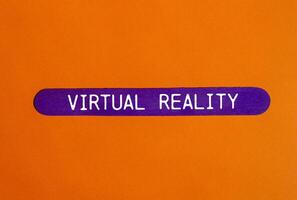 Virtual reality message written on purple wooden stick with orange background. Conceptual virtual reality symbol. Copy space. photo