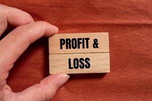 Profit and loss message written on wooden blocks with brown background. Conceptual profit and loss symbol. Copy space. photo