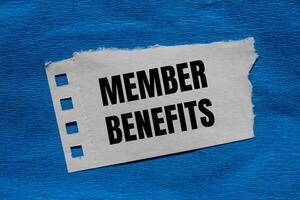 Member benefits message written on ripped torn paper piece with blue background. Conceptual member benefits symbol. Copy space. photo