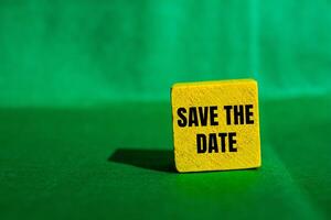 Save the date message written on yellow wooden cube with green background. Conceptual save the date symbol. Copy space. photo