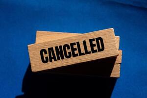 Cancelled message written on wooden blocks with blue background. Conceptual cancelled symbol. Copy space. photo