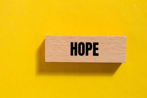 Hope message written on wooden block with yellow background. Conceptual hope symbol. Copy space. photo